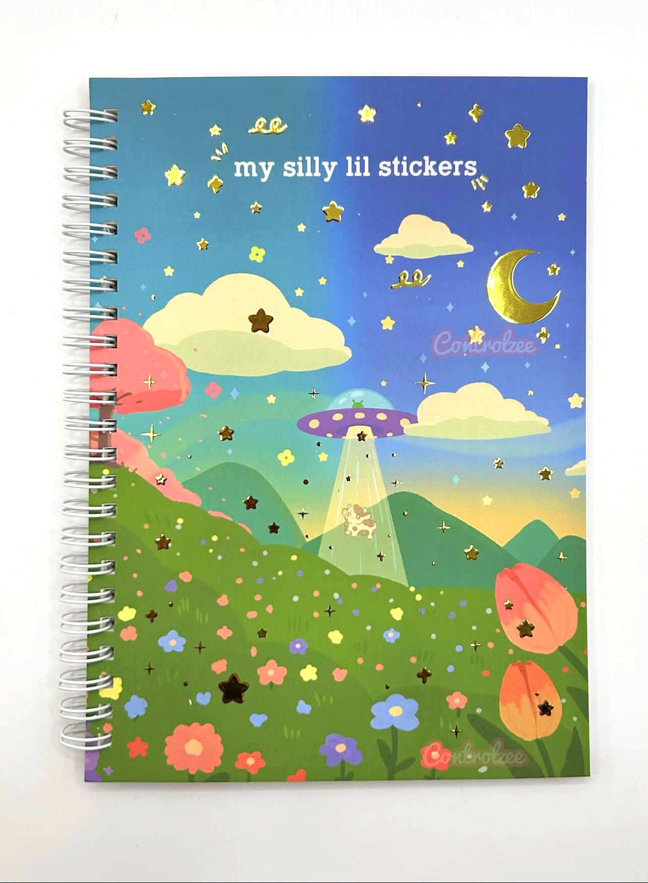 Notebook with a colorful illustration of a UFO over a landscape with flowers and stars on the cover.
