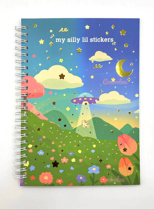 Notebook with a colorful illustration of a UFO over a landscape with flowers and stars on the cover.